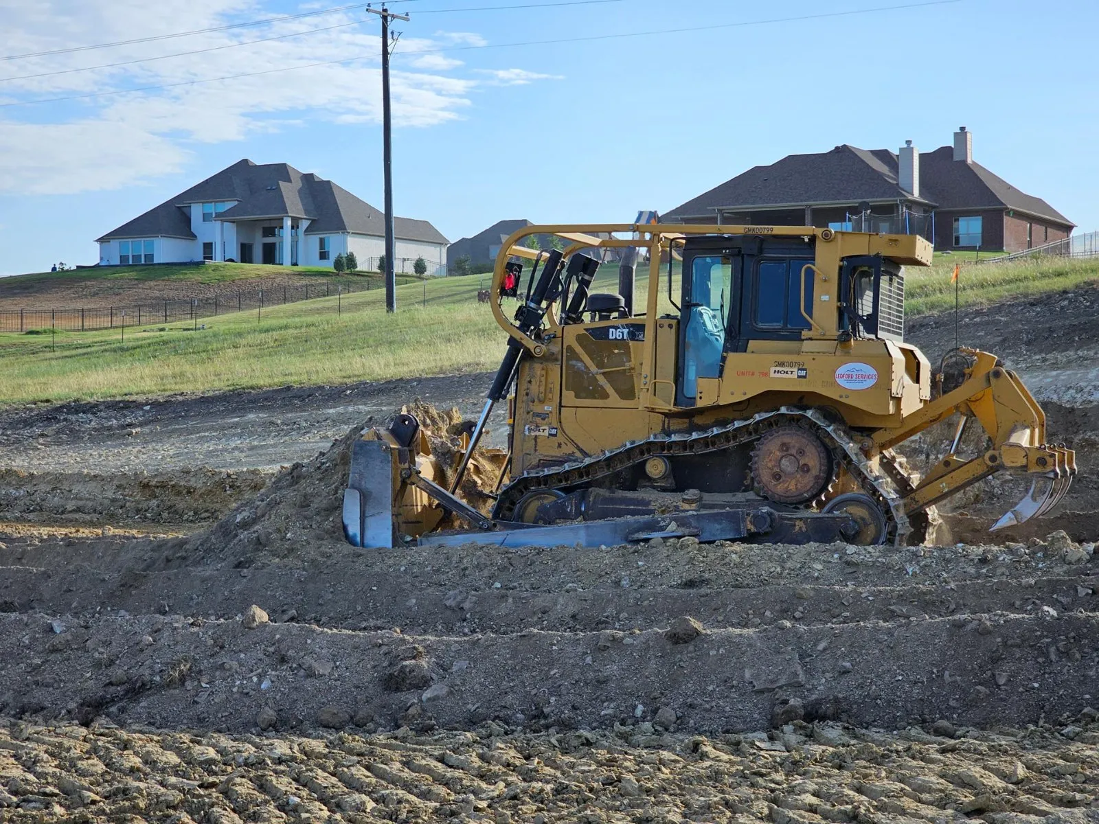 Ledford Services CAT dozer grading a development pad in front of new homes