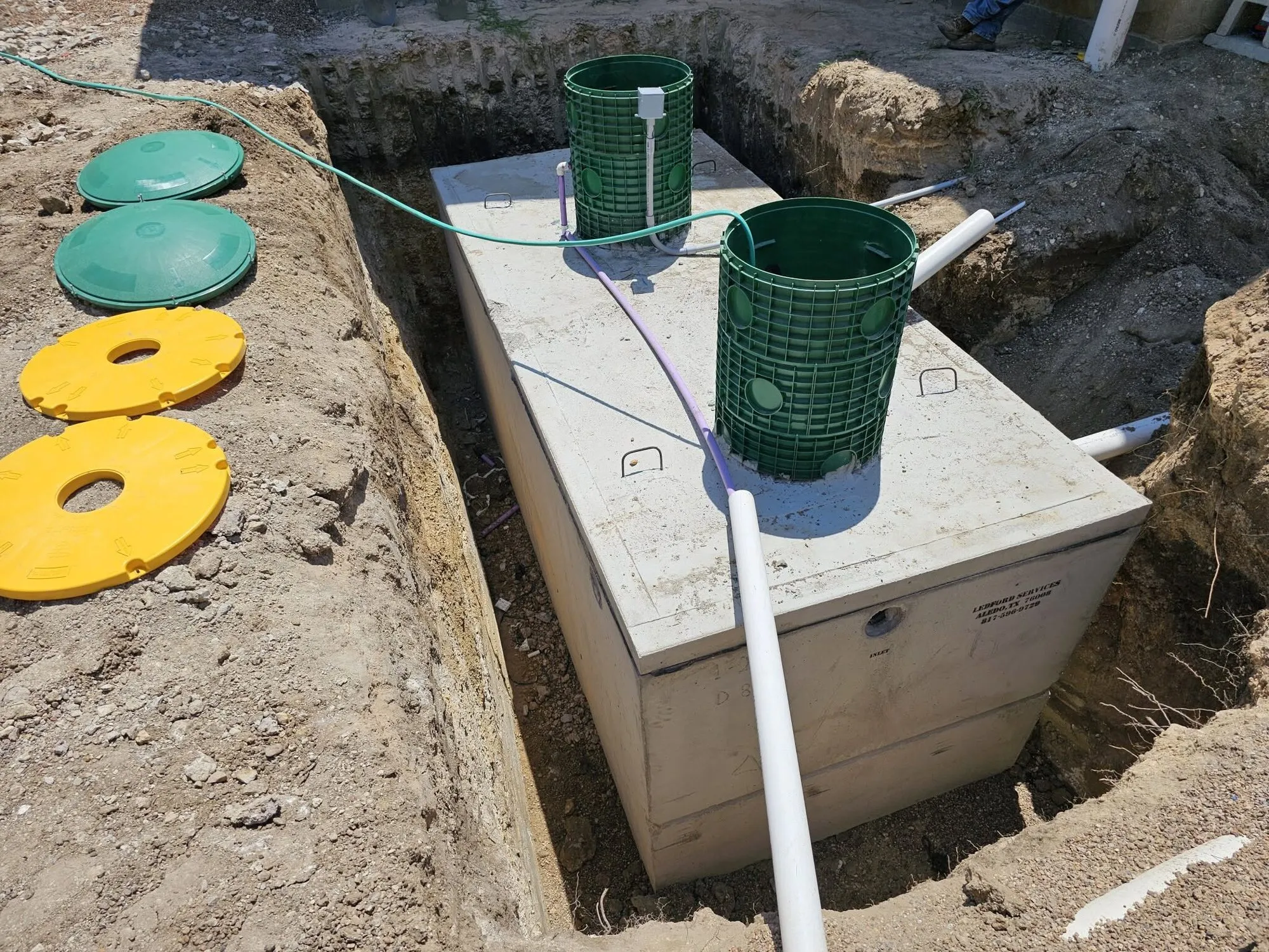A septic tank opened up with risers and lids off during service